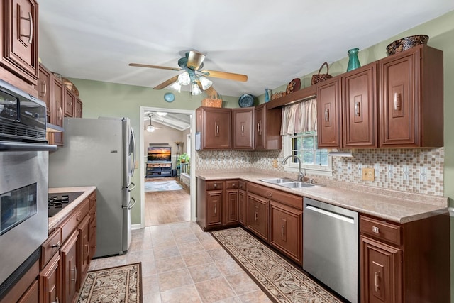 kitchen with lofted ceiling, ceiling fan, decorative backsplash, stainless steel appliances, and sink