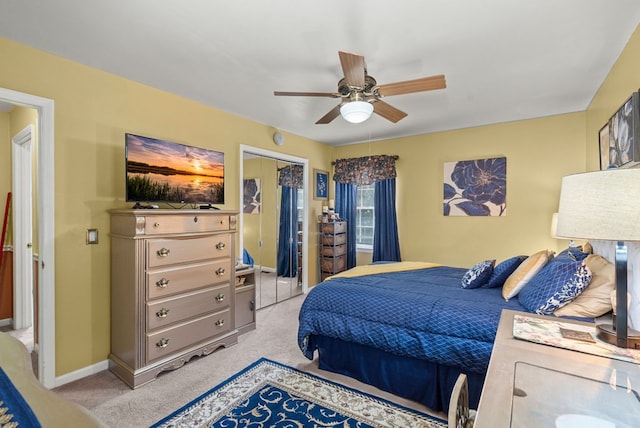 bedroom with ceiling fan, a closet, and light carpet