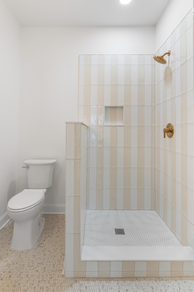 full bathroom with tile patterned floors, baseboards, toilet, and a tile shower