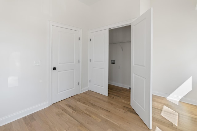 unfurnished bedroom featuring a closet, light wood-type flooring, and baseboards