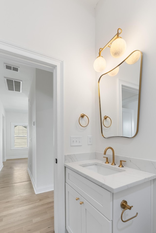 bathroom featuring vanity, wood finished floors, visible vents, and baseboards