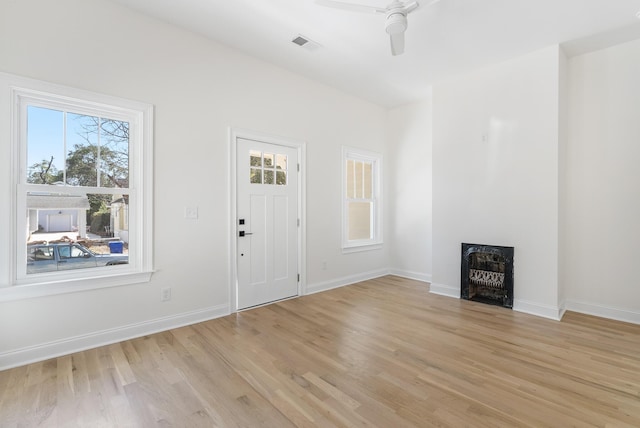 entrance foyer with light wood-type flooring, visible vents, a ceiling fan, a fireplace, and baseboards