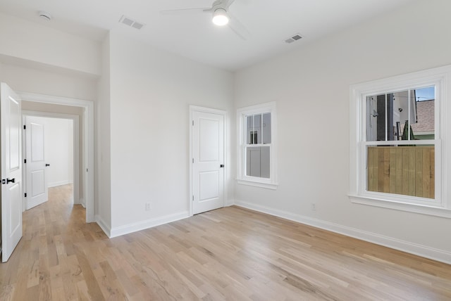 empty room with light wood-type flooring, visible vents, baseboards, and a ceiling fan