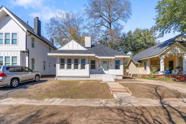 view of front of home with a porch, roof with shingles, and a chimney