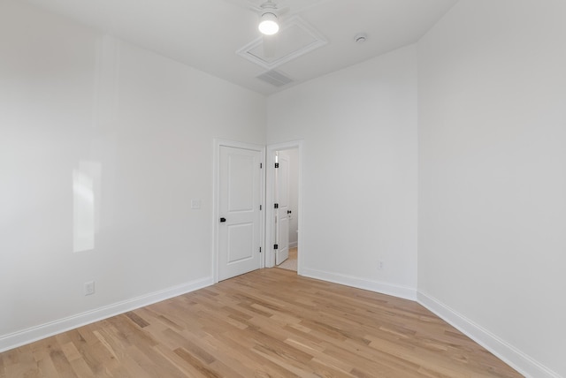 unfurnished room with visible vents, baseboards, light wood-style floors, and attic access