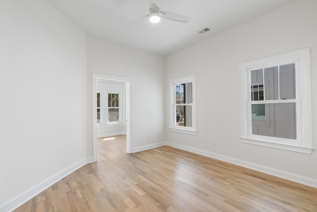 empty room featuring light wood finished floors, visible vents, a ceiling fan, and baseboards