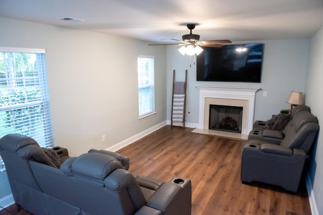 living area featuring wood finished floors, ceiling fan, a fireplace, and baseboards