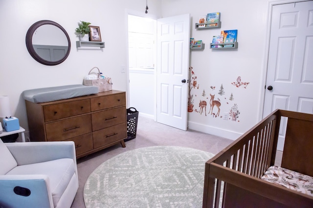 bedroom featuring light colored carpet, a crib, and baseboards