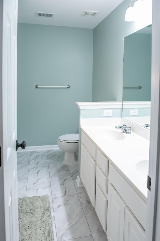 full bath with marble finish flooring, toilet, double vanity, and baseboards