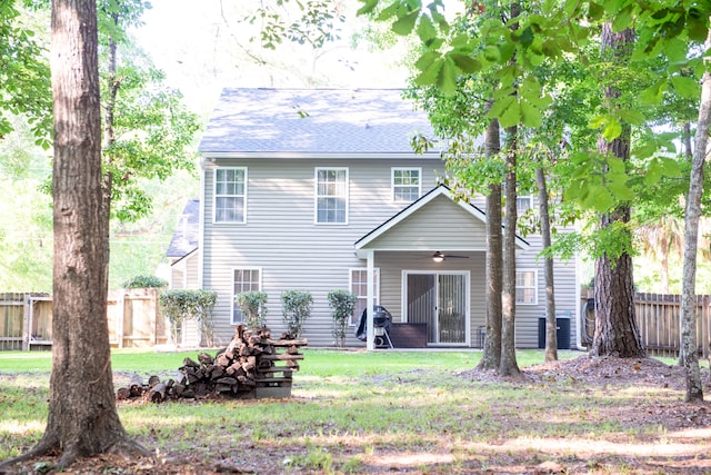 back of house with a ceiling fan and roof with shingles