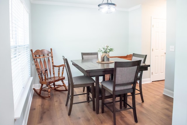 dining room with ornamental molding, wood finished floors, and baseboards