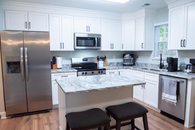 kitchen featuring stainless steel appliances, light wood-type flooring, a sink, and white cabinets