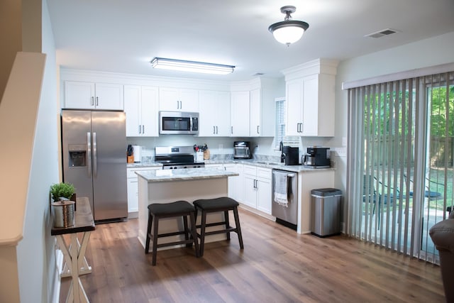 kitchen featuring appliances with stainless steel finishes, wood finished floors, white cabinetry, and a kitchen island