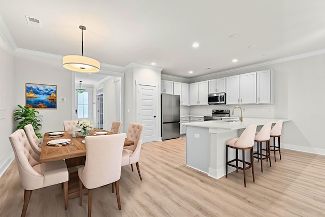 5133 Park Creek Ave, North Charleston, SC 29418 - kitchen featuring appliances with stainless steel finishes, a peninsula, crown molding, a breakfast bar, and light wood-style flooring