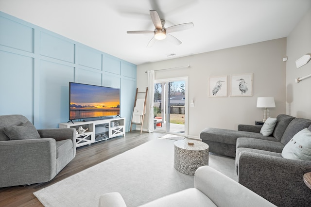 living room with dark wood-type flooring, a ceiling fan, and visible vents