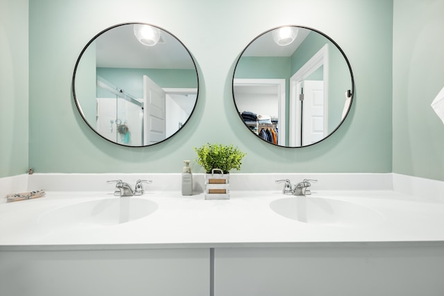 bathroom featuring double vanity, a shower with shower door, and a sink