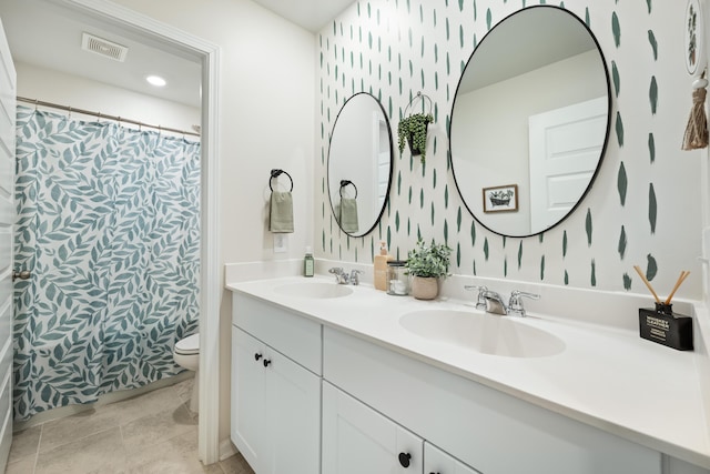 bathroom featuring a sink, visible vents, toilet, and wallpapered walls