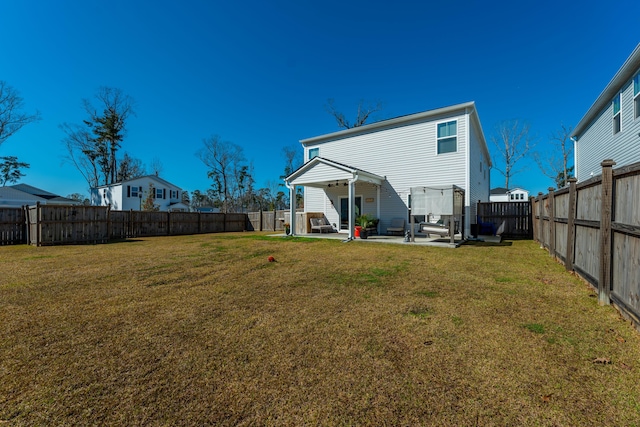 rear view of property with a yard, a patio area, and a fenced backyard