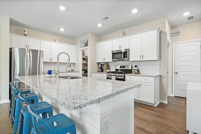 kitchen with a sink, visible vents, appliances with stainless steel finishes, and white cabinets