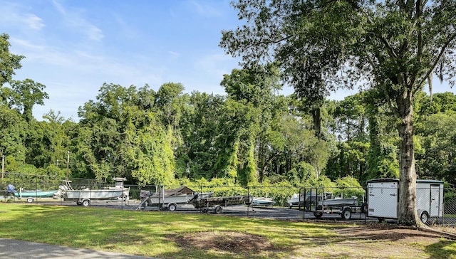 view of home's community with a yard, a view of trees, and fence