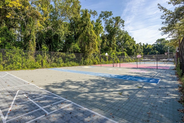 view of tennis court with community basketball court and fence