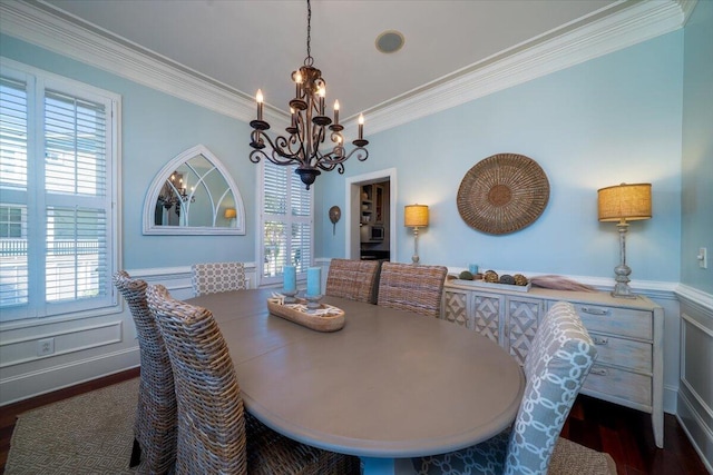 dining room with a wainscoted wall, a decorative wall, an inviting chandelier, ornamental molding, and wood finished floors