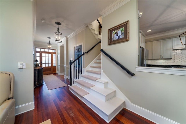 entrance foyer with dark wood-style floors, ornamental molding, stairway, and baseboards