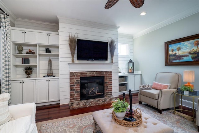 living area with ceiling fan, a fireplace, ornamental molding, and wood finished floors