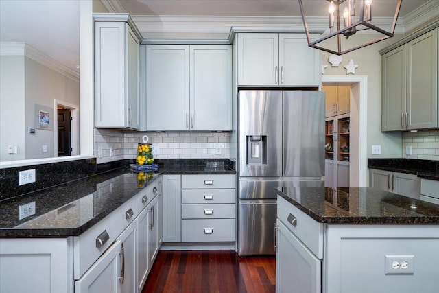 kitchen with a peninsula, dark wood-type flooring, stainless steel refrigerator with ice dispenser, tasteful backsplash, and crown molding