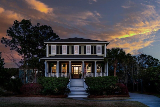 colonial house featuring covered porch, driveway, and stairway