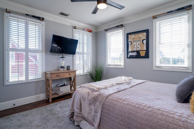 bedroom with baseboards, visible vents, crown molding, and wood finished floors