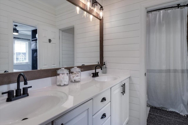 bathroom with double vanity, a shower with curtain, a sink, and wood walls