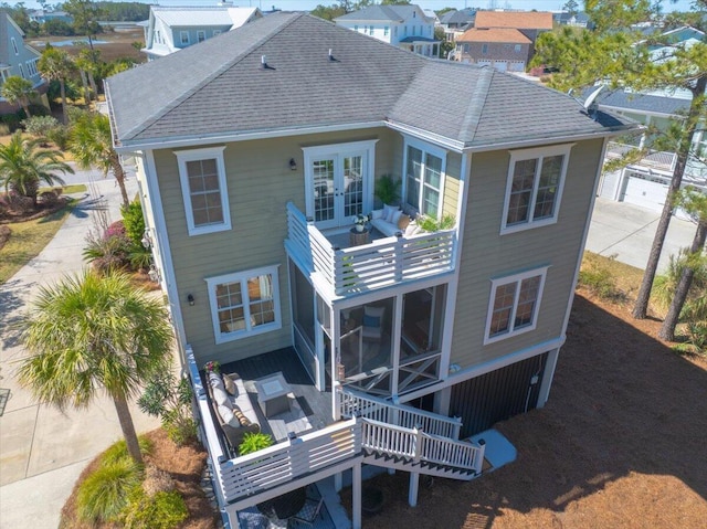 back of property featuring french doors, a shingled roof, and a balcony