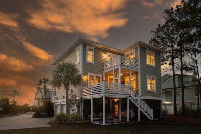 rear view of property with a patio, stairway, an attached garage, a balcony, and driveway