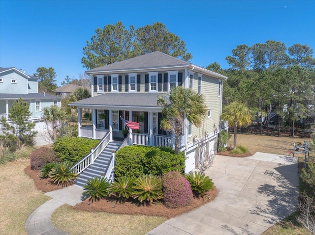 view of front facade with a garage, covered porch, concrete driveway, and stairs