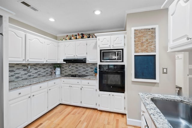 kitchen featuring black appliances, extractor fan, light wood-style floors, tasteful backsplash, and white cabinetry