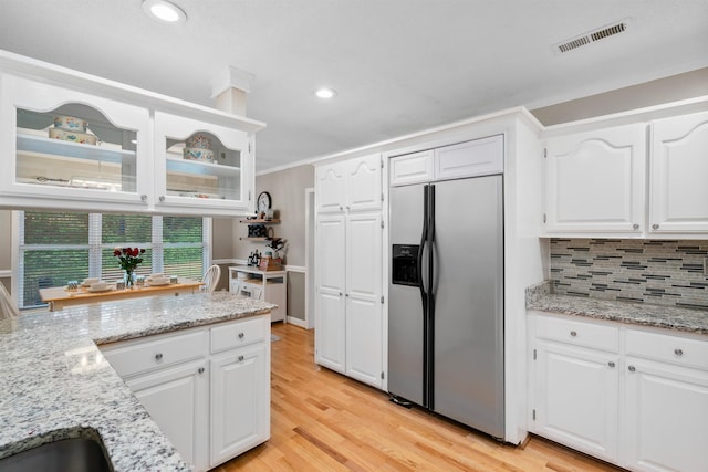 kitchen featuring stainless steel refrigerator with ice dispenser, light wood-style flooring, glass insert cabinets, white cabinets, and recessed lighting
