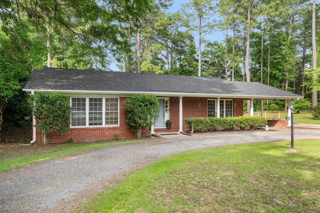 ranch-style house with curved driveway, a front lawn, brick siding, and covered porch