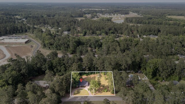 aerial view of property and surrounding area featuring a heavily wooded area and property boundaries highlighted