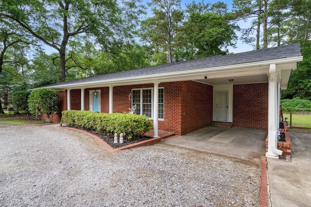 view of front facade with brick siding, an attached carport, and driveway