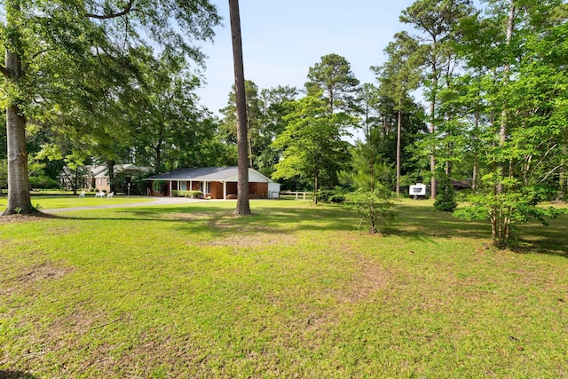 view of grassy yard with view of wooded area