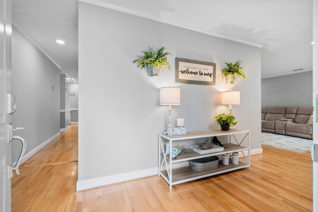 corridor with wood finished floors, ornamental molding, baseboards, and recessed lighting