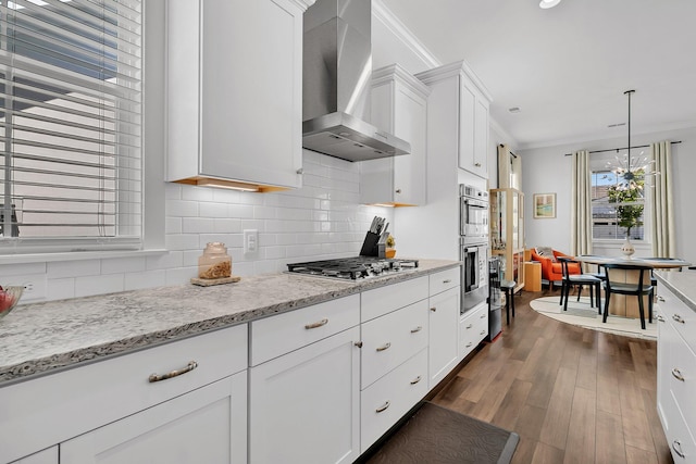 3529 Habenaria Rd Unit 33, Mount Pleasant, SC 29466 - kitchen featuring wall chimney range hood, appliances with stainless steel finishes, crown molding, dark wood finished floors, and white cabinets