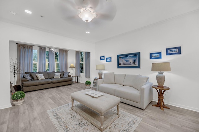 living area with light wood-style flooring, ornamental molding, baseboards, and ceiling fan