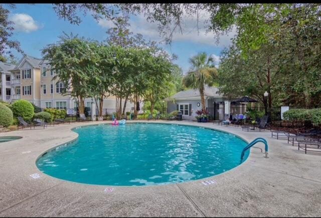 community pool with a patio and fence