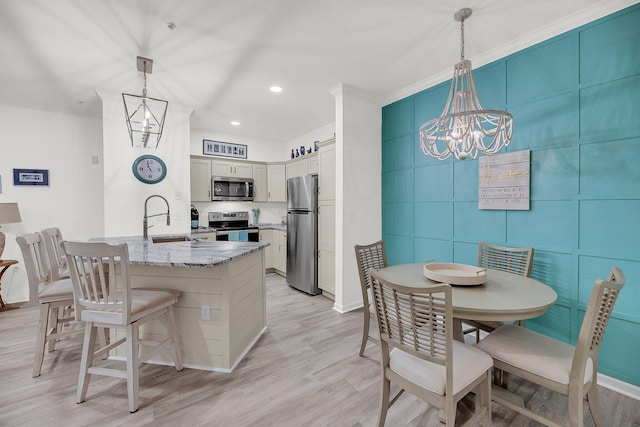 kitchen featuring light wood finished floors, crown molding, light stone countertops, appliances with stainless steel finishes, and a peninsula