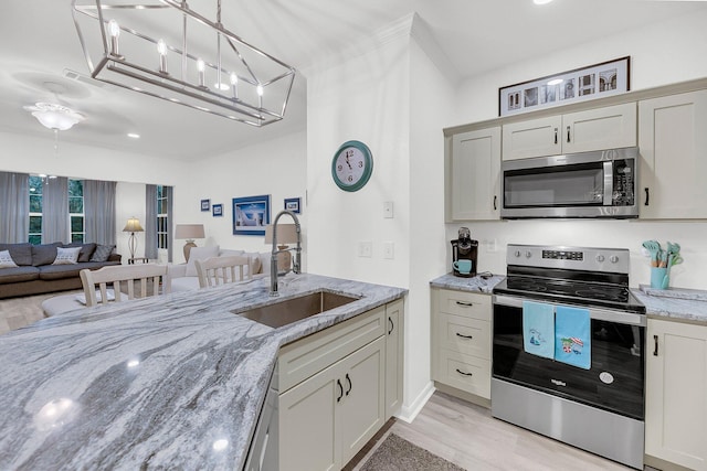 kitchen with light wood finished floors, open floor plan, stainless steel appliances, and a sink