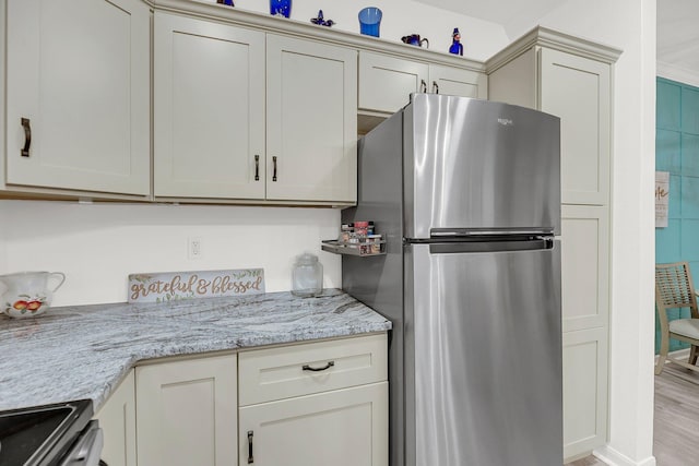 kitchen featuring light stone counters, appliances with stainless steel finishes, and light wood-style floors