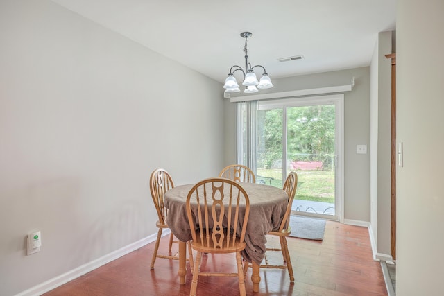 dining space featuring baseboards, wood finished floors, visible vents, and a chandelier