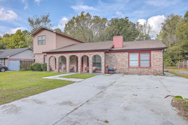 view of front of house featuring fence, a chimney, a front lawn, concrete driveway, and brick siding